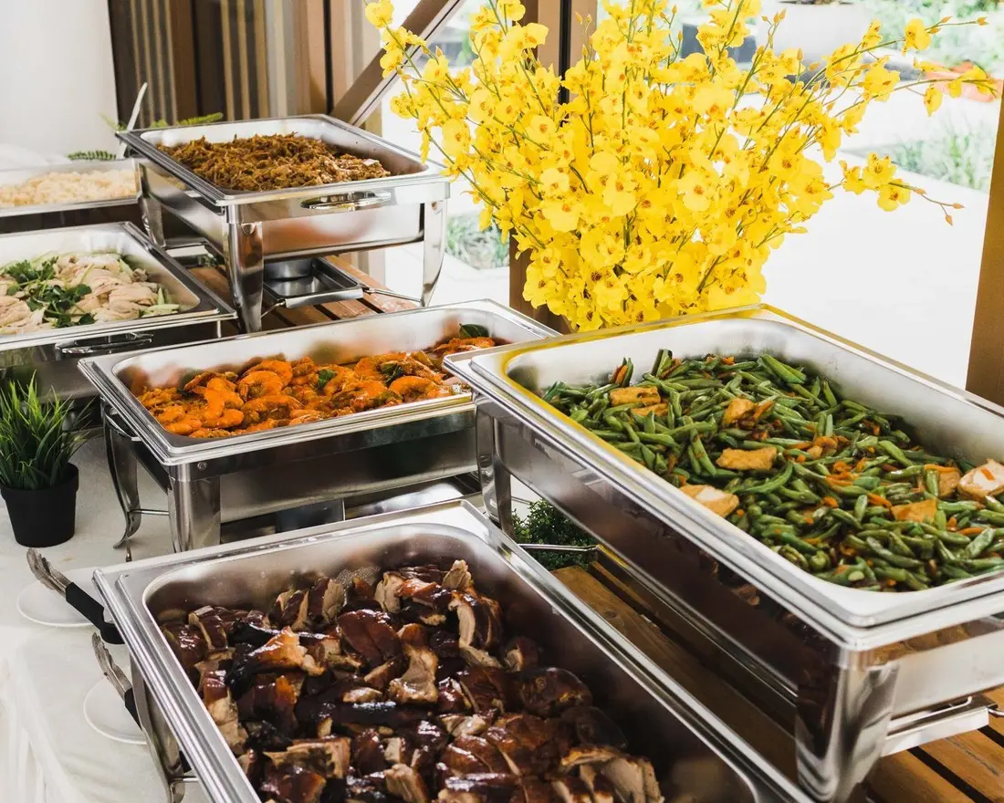 Buffet catering setup with food warmers and local dishes at an event in Singapore