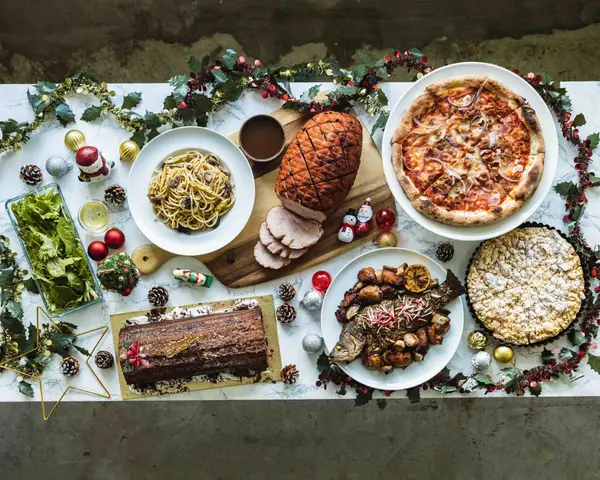 Christmas buffet catering spread with baked ham, pizza, pasta, grilled fish and log cake