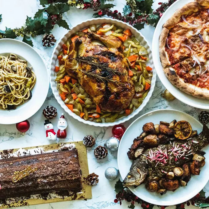 Christmas buffet catering spread with roast chicken, pizza, pasta and log cake