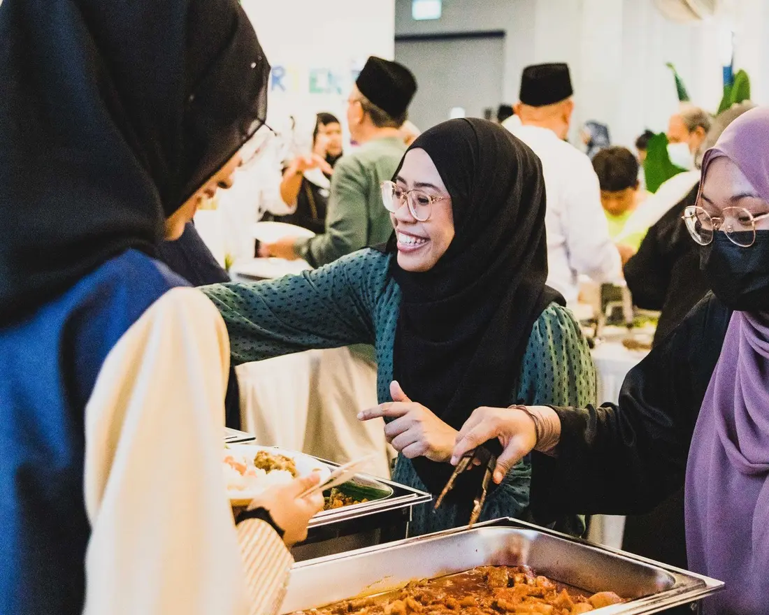 Malay buffet catering line with rendang and satay at a Singapore event