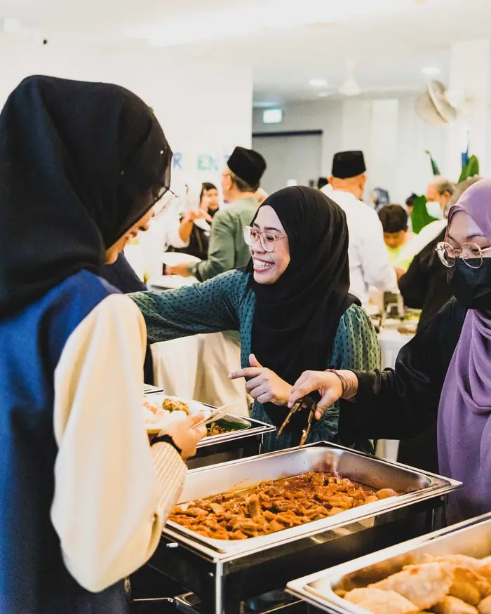 Guests at a Hari Raya company event serving themselves from a halal buffet