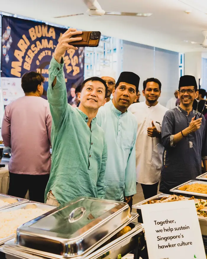Colleagues taking a selfie at a Hari Raya corporate event with halal catering