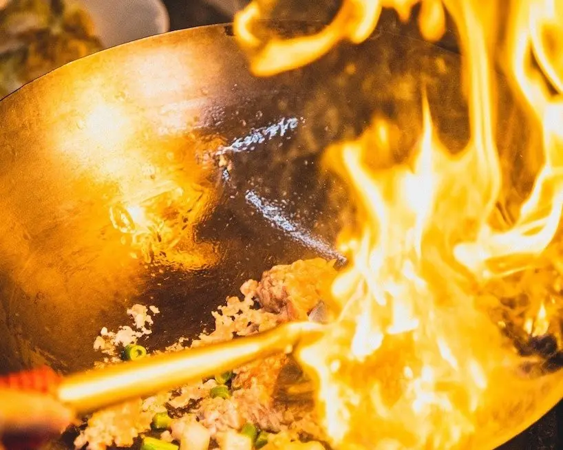 Wok cooking over high heat for zi char style catering in Singapore